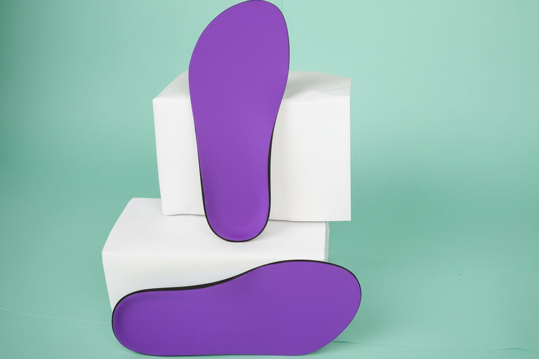 two CustomTread orthotic insoles in purple stacked on white geometric blocks against mint green background