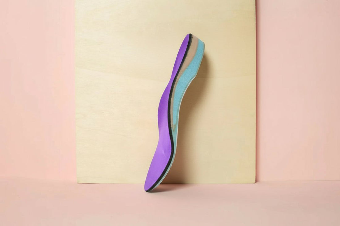 CustomTread orthotic insole in purple and teal standing upright on cream background, product photography