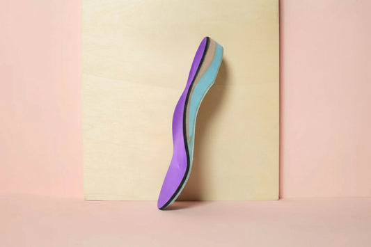 CustomTread orthotic insole in purple and teal standing upright on cream background, product photography
