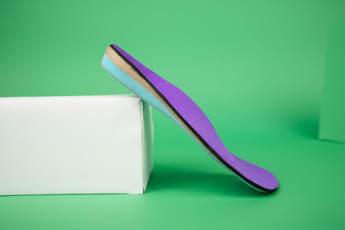 CustomTread orthotic insole leaning against a white box on green background, product photography